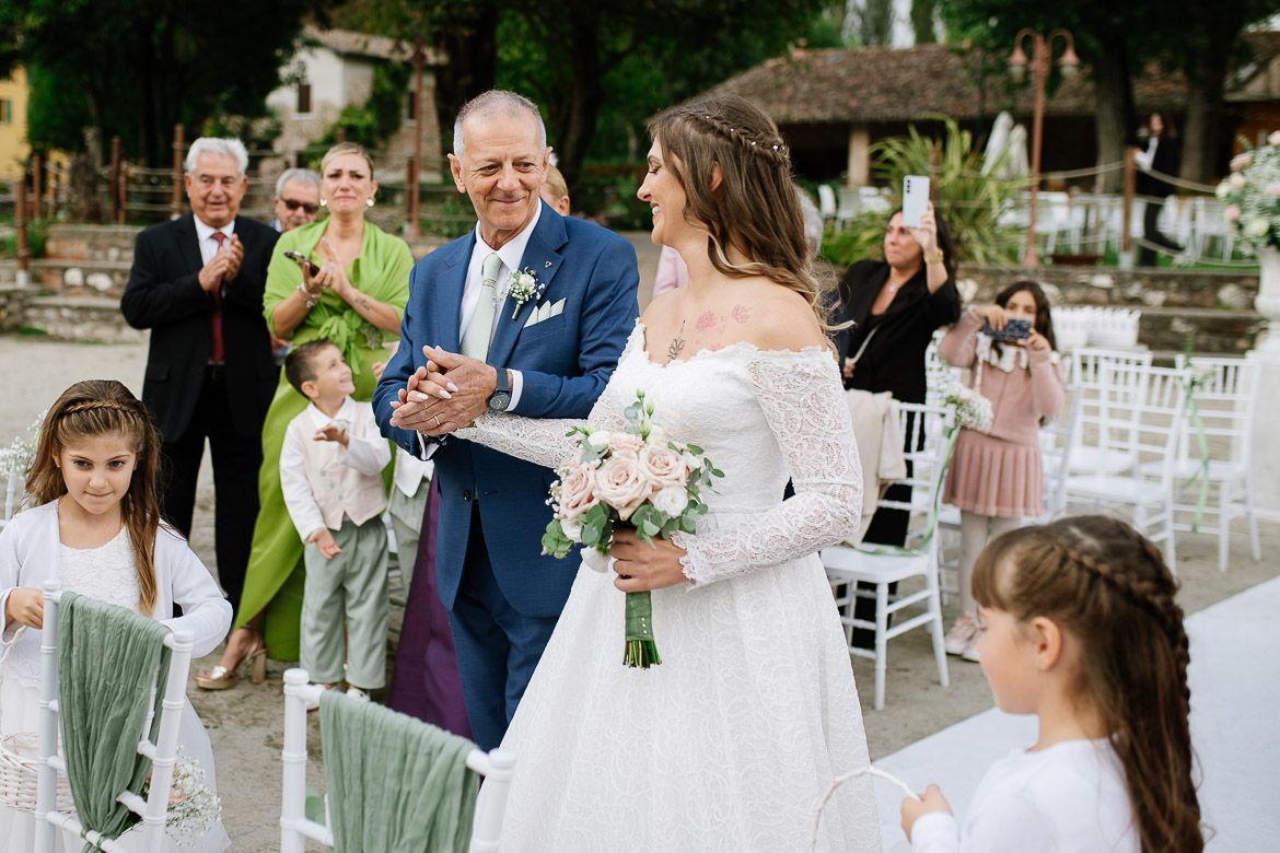 Wedding ceremony guests seated in white chairs at outdoor waterfront venue.