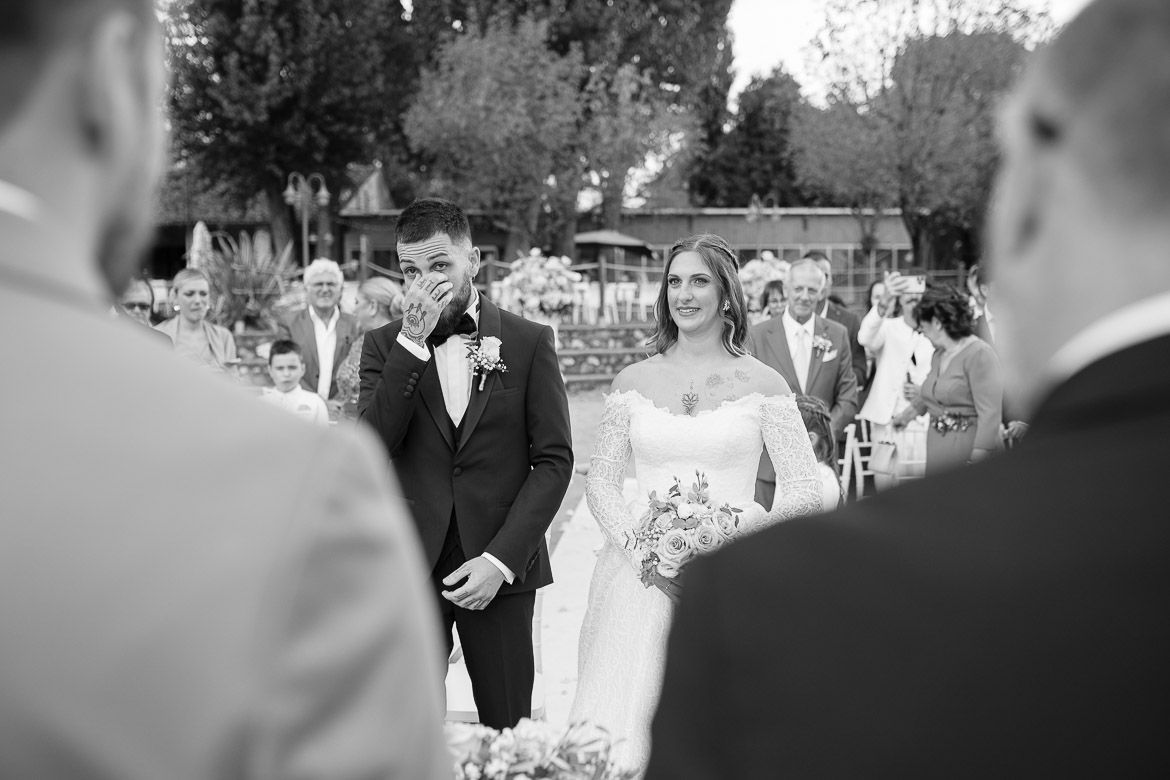 Black and white photo captures candid moments during an outdoor wedding reception.