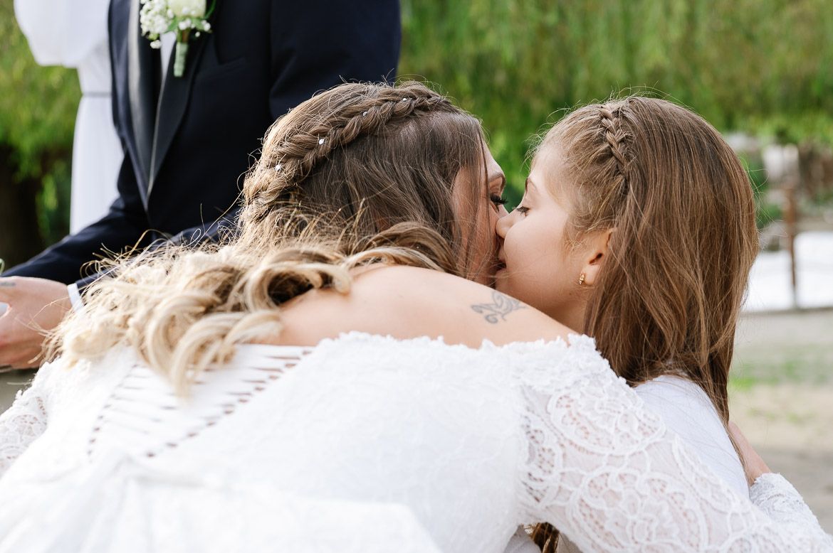 Two people in wedding attire sharing an intimate moment outdoors.