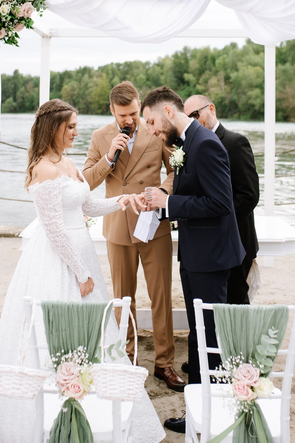 Waterfront wedding ceremony with pink floral arrangements and mint green accents.