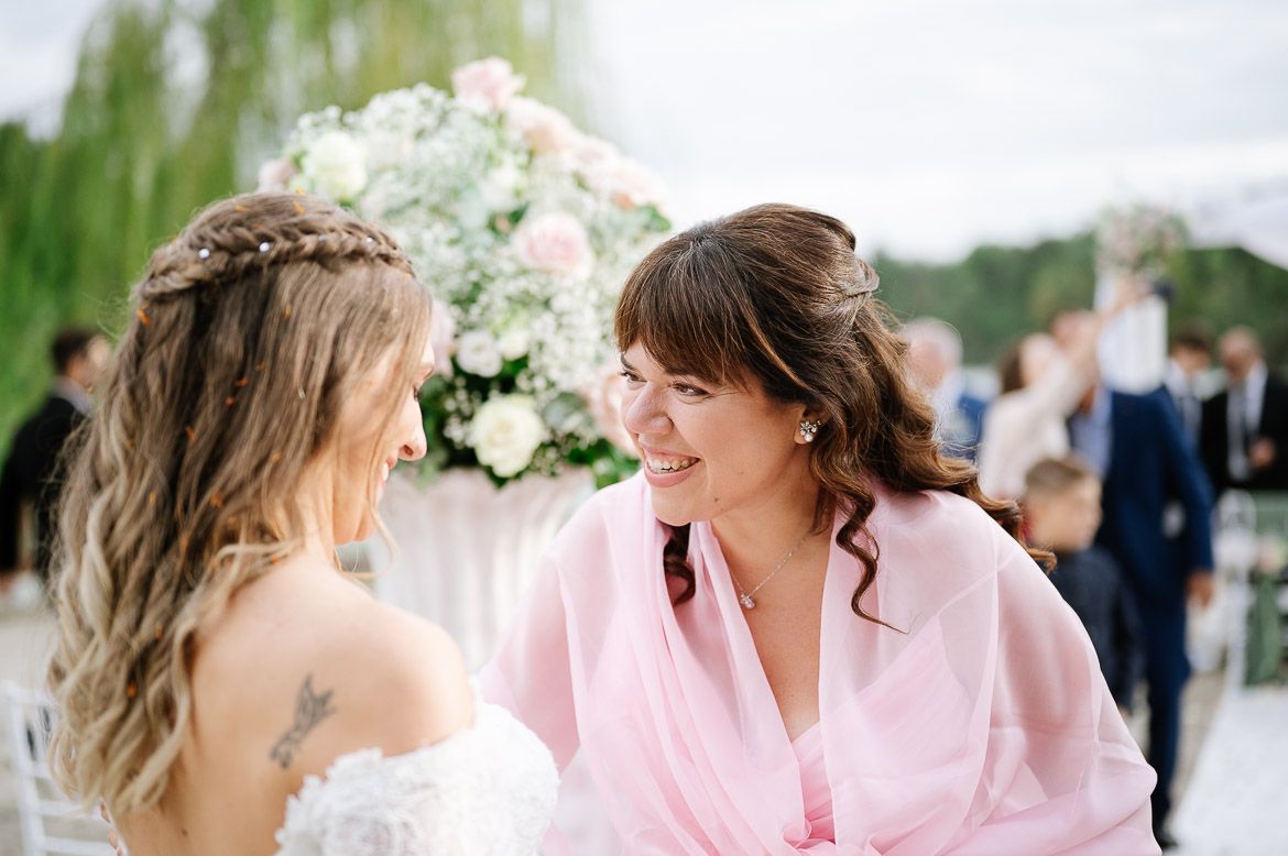 Wedding party in soft pink dresses stands together outdoors during a sunny summer celebration.