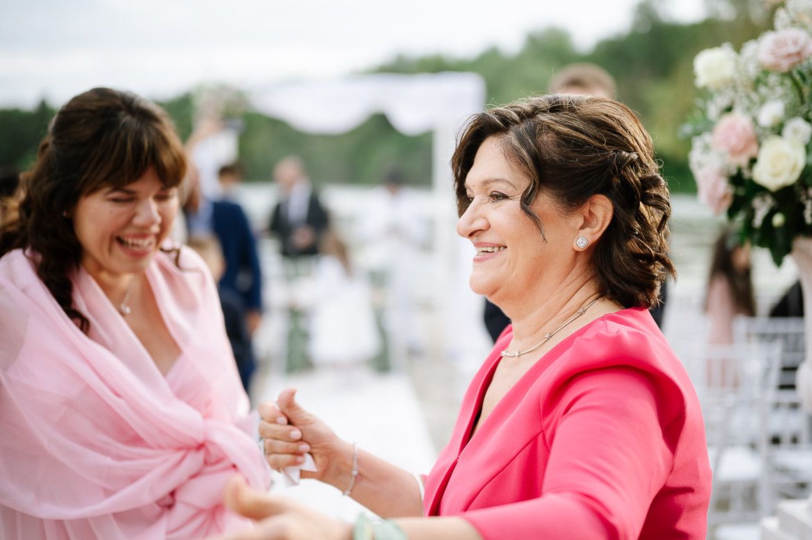 A group of women in pink outfits smile and laugh together during an outdoor celebration event.