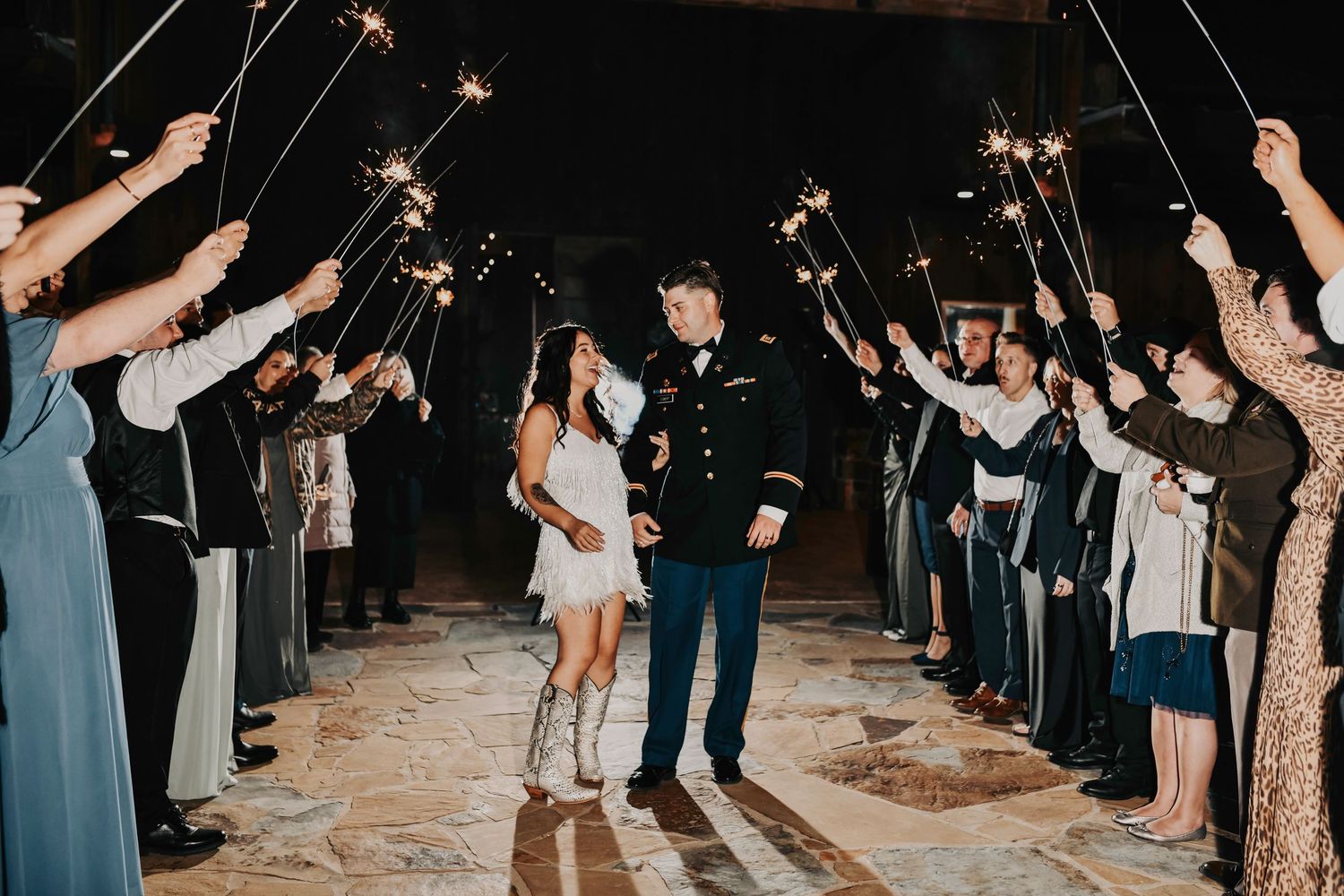 Wedding send-off with guests waving sparklers as the couple runs toward their getaway car.