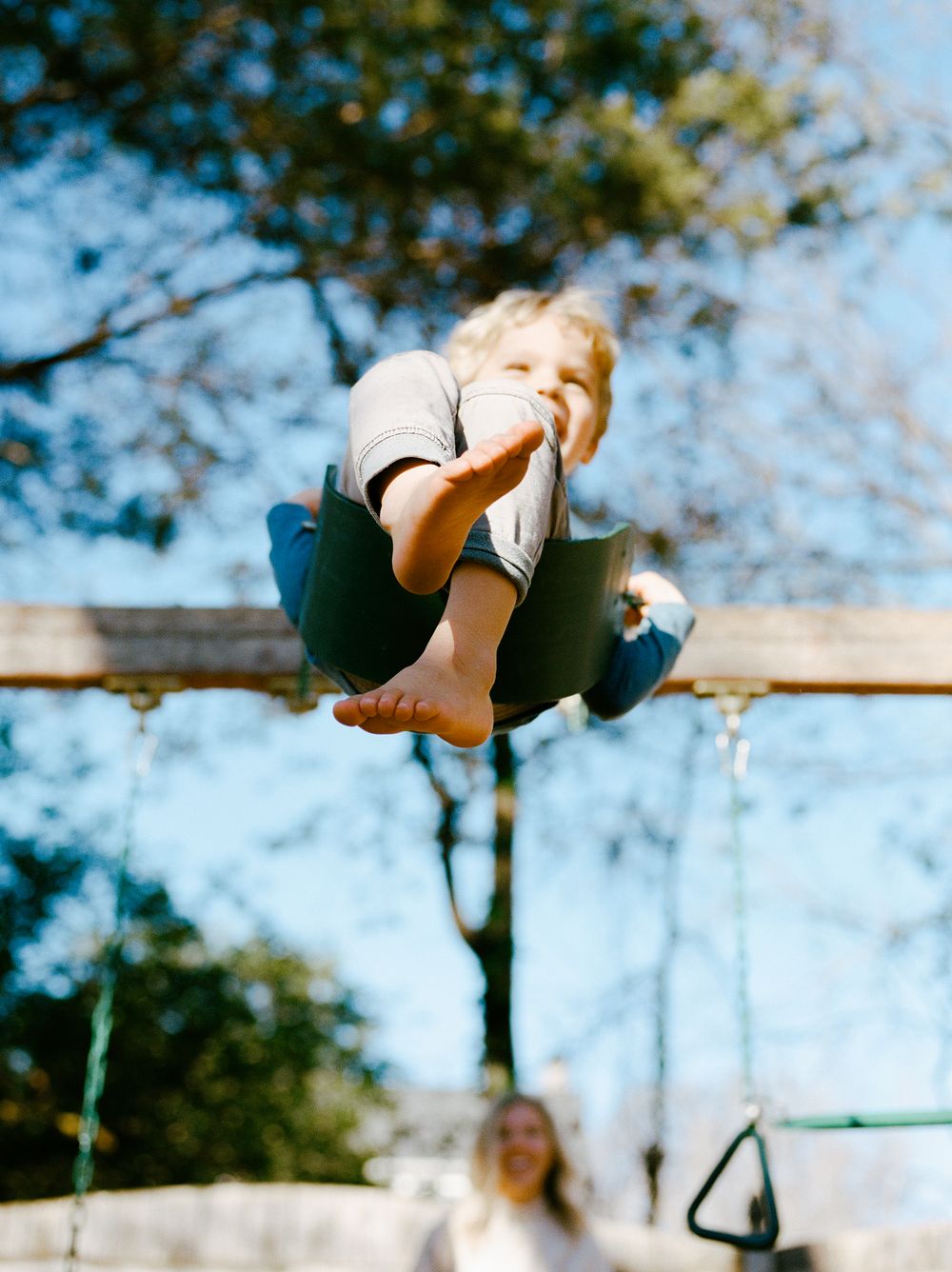 Action shots of someone swinging high on a playground swing set against a blue sky.