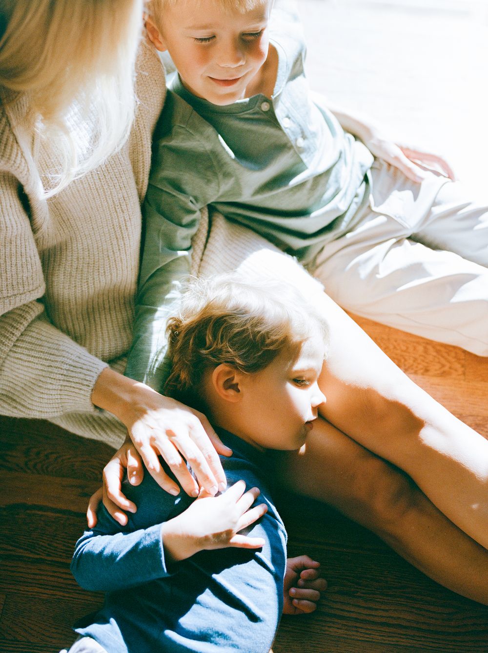 Tender moment captured in sunlit indoor setting showing gentle interaction and rest.