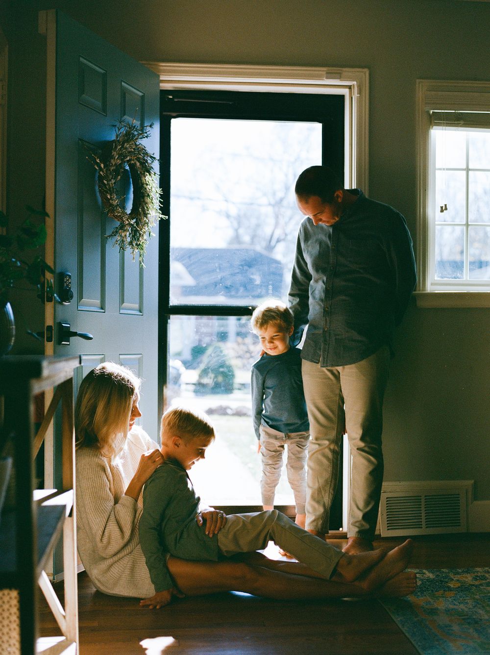 Sunlit interior scene with people by windows in a home setting.