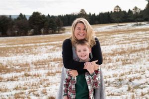 Family enjoying a winter photoshoot outdoors in the snow with evergreen trees in the background.