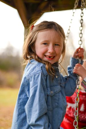 Playful moment captured on a swing set wearing denim on an autumn day.