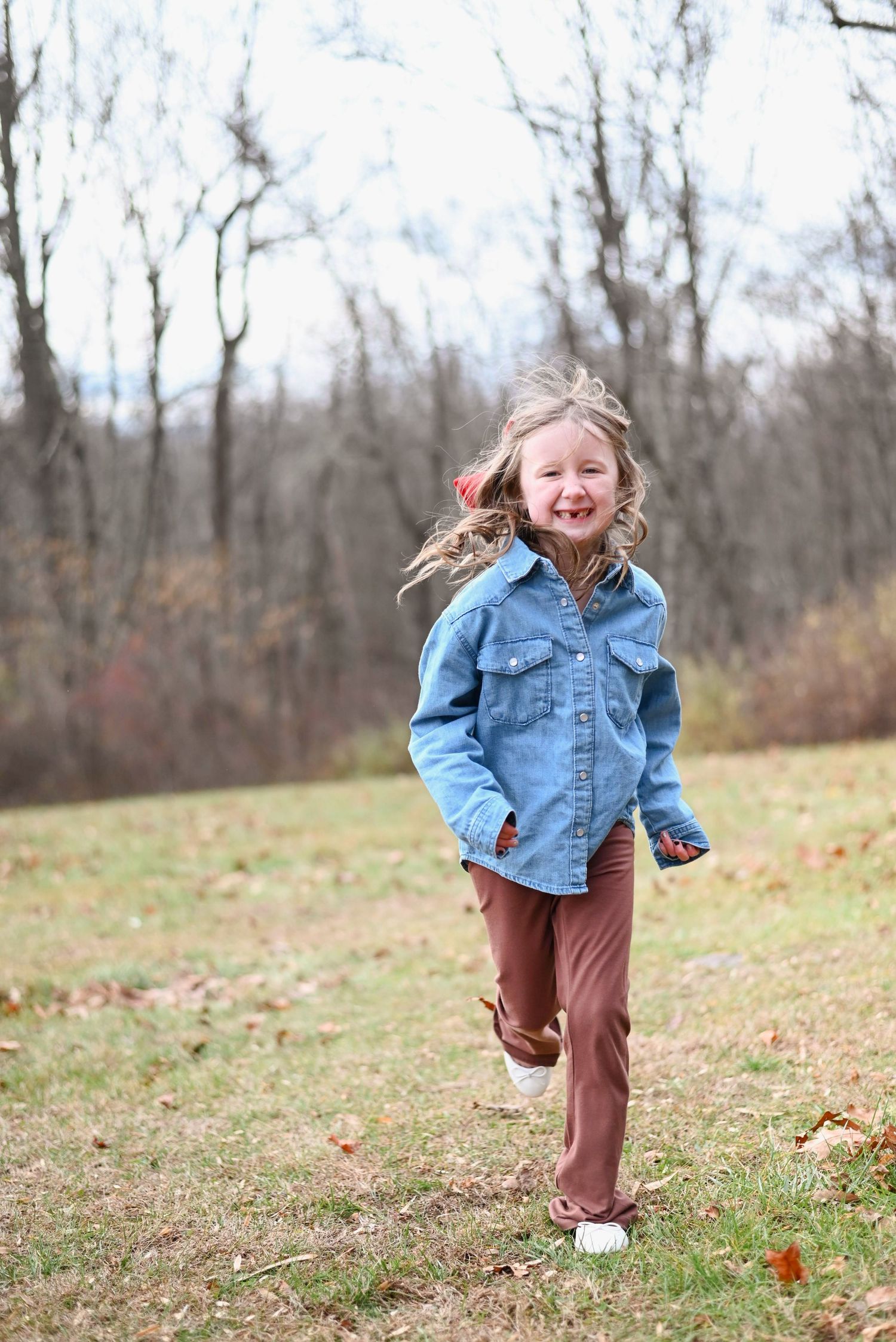 Running and laughing on a crisp autumn day in casual denim attire.
