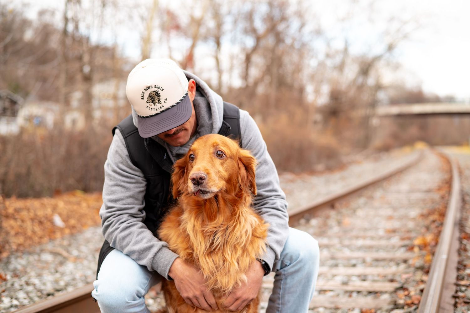 Golden retriever poses on train tracks during autumn outdoor photography session.