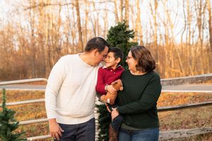 Candid outdoor family photos taken near a wooden fence during autumn.