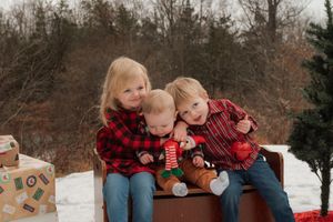 Family in coordinating buffalo plaid outfits cuddles together during holiday photo session.