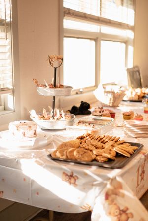 Party table setup with tiered dessert stands and cookies in warm sunlit room.
