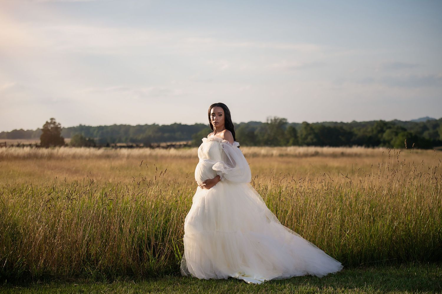 A wedding dress portrait in a golden meadow at sunset capturing an ethereal bridal moment.