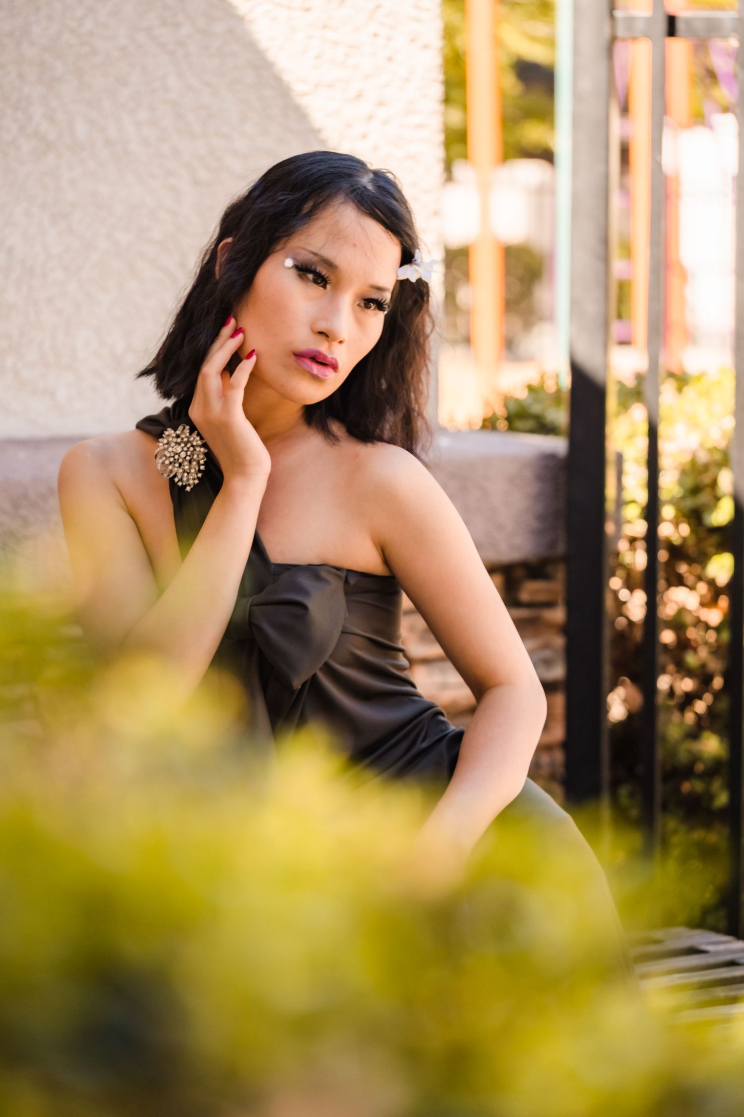 A model in a Aquatico dress poses outdoors before a fashion show in vacaville ca with blurred foliage in the foreground.