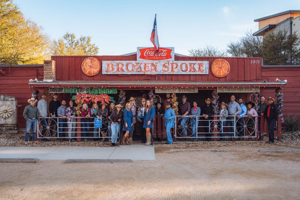 A long line of customers waits outside a brick storefront with Pro-Fit Sport signage during a busy shopping day.