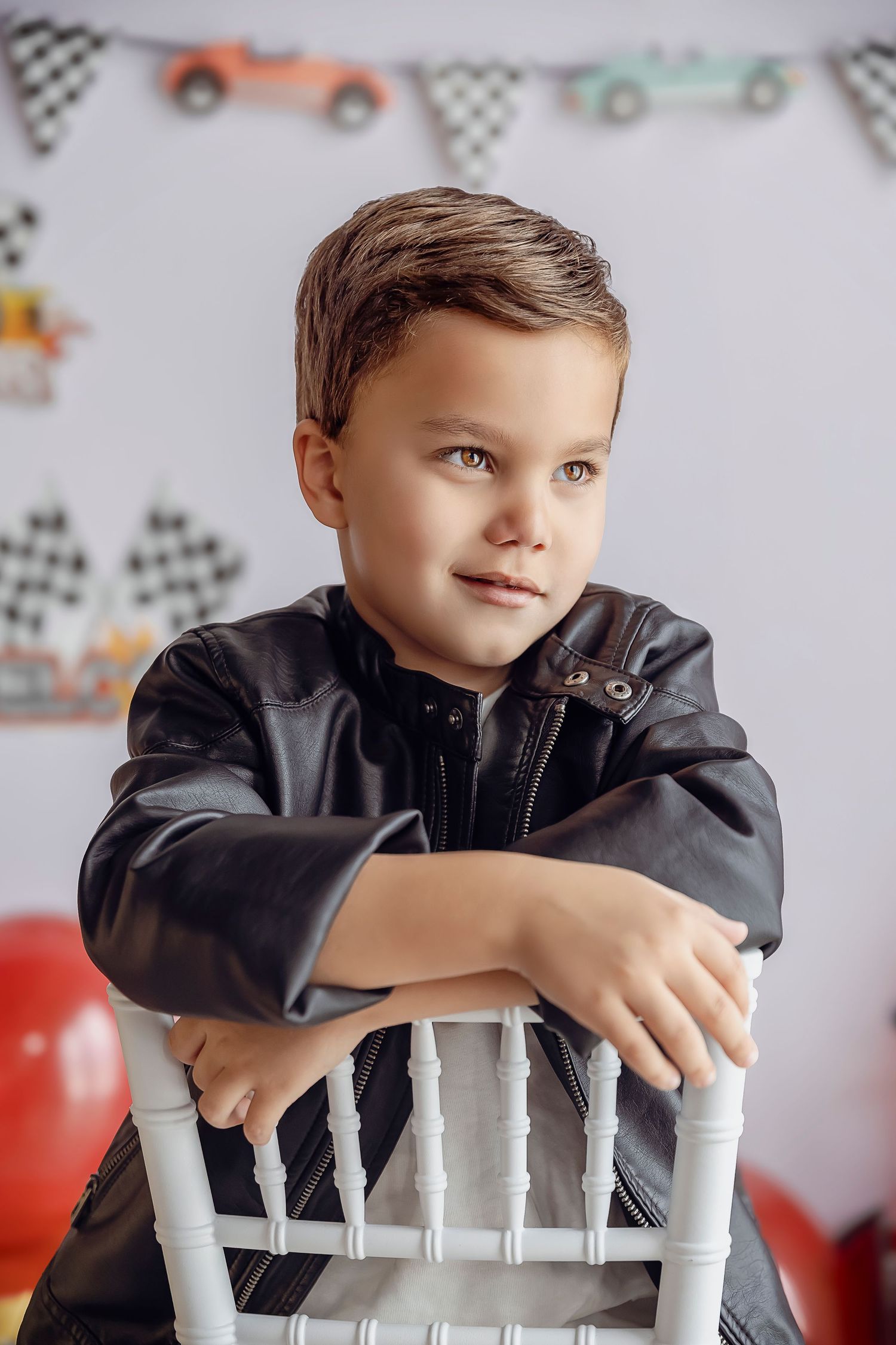 Fotografa Infantil en Ponce obtiene imagenes de un nino bello con ojos claros sonriendo al horizonte utilizando una chaqueta de cuero.