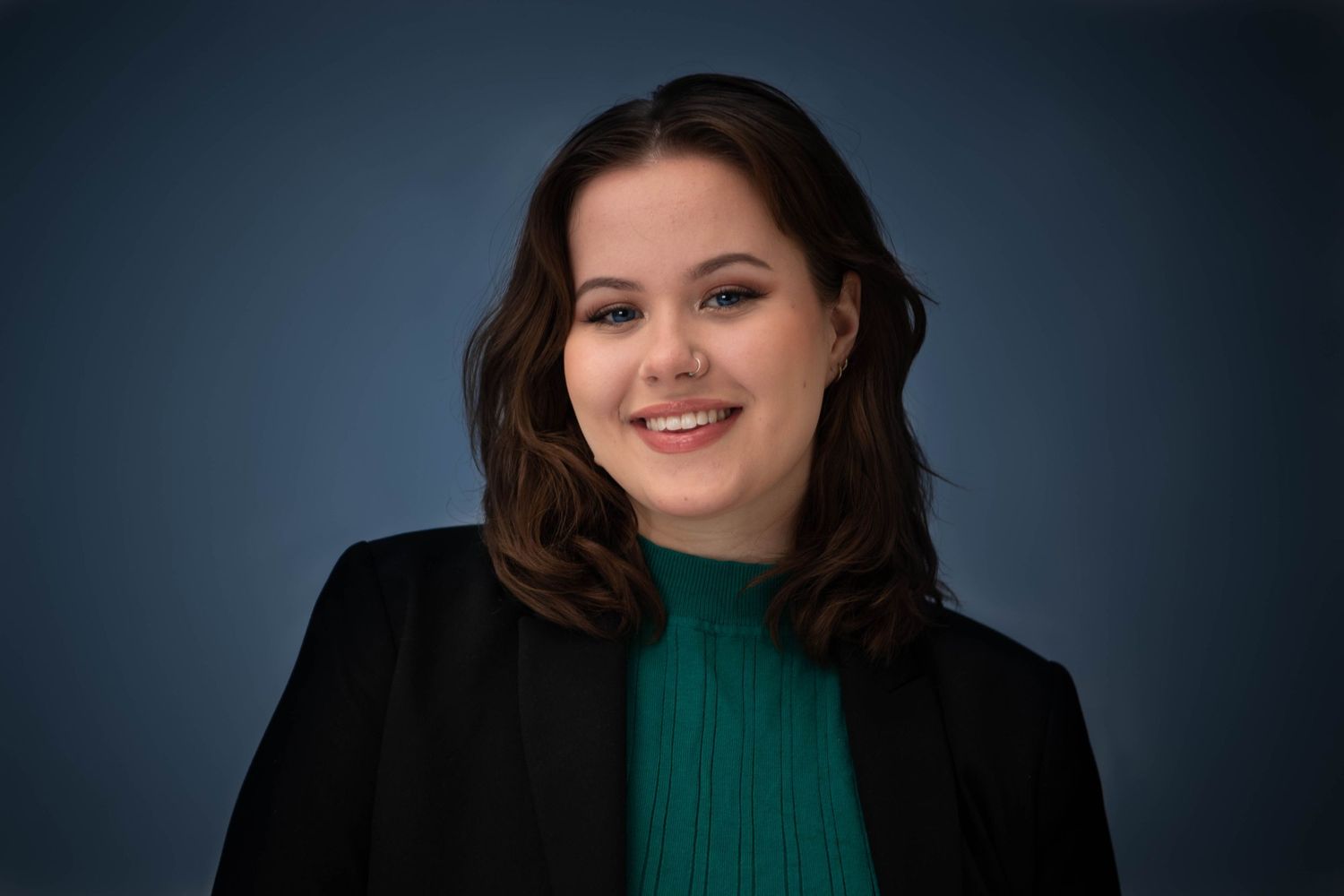 Profesjonelt headshot av dame i blazer mot mørk bakgrunn, CV-foto og bedriftsportrett av Prospectxmedia.