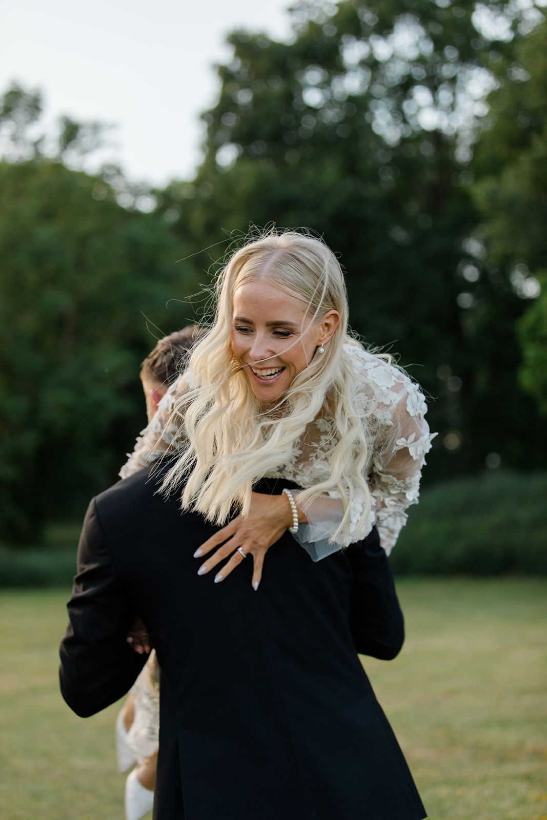 A joyful couple shares a playful piggyback moment outdoors in a green park setting.