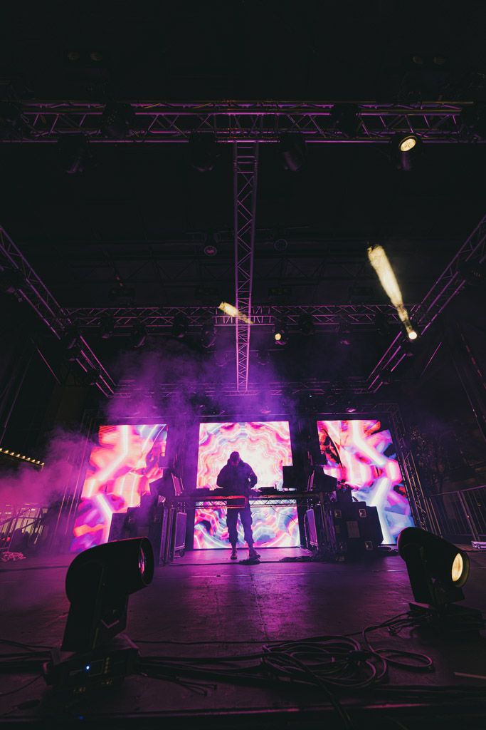Concert stage setup with pink lighting and LED screens creating an immersive atmosphere.