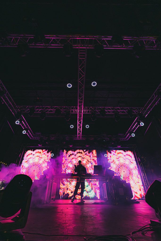 Concert stage with pink neon lighting design and geometric truss structures.