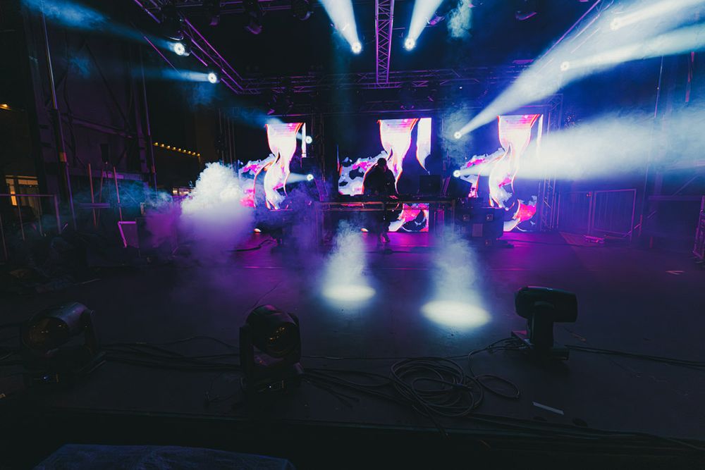 Concert venue illuminated with dynamic blue and purple lighting effects creating an ethereal atmosphere.