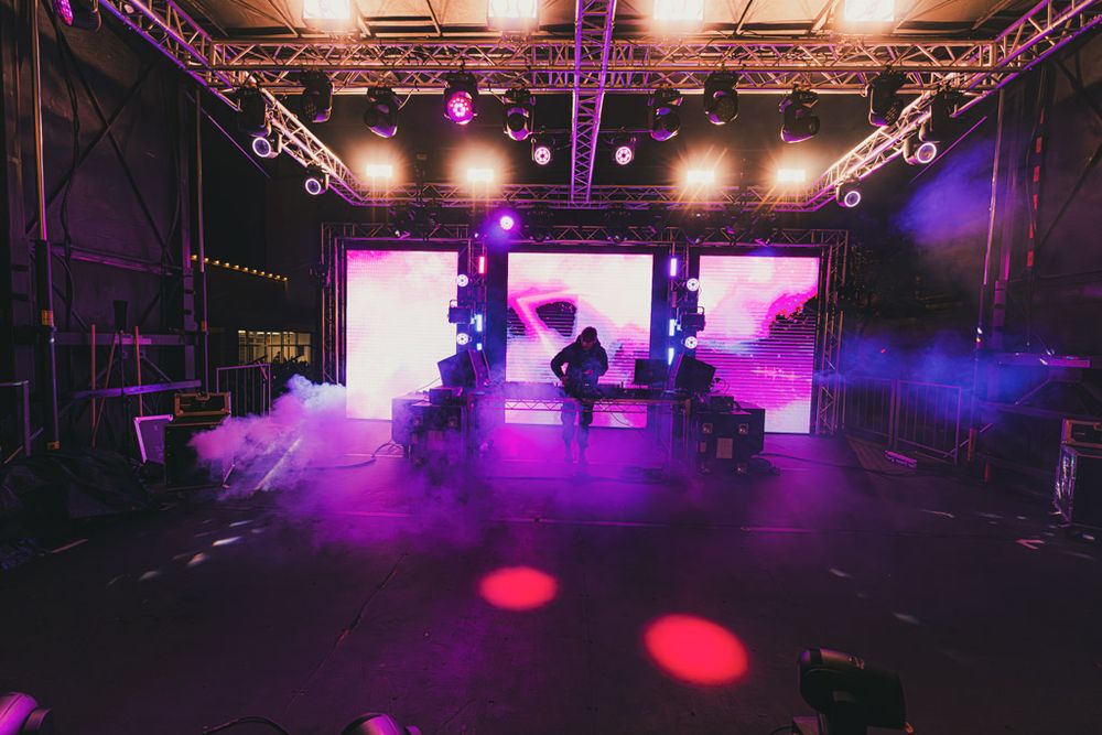 Empty stage setup with dramatic purple and red lighting rigs mounted overhead.