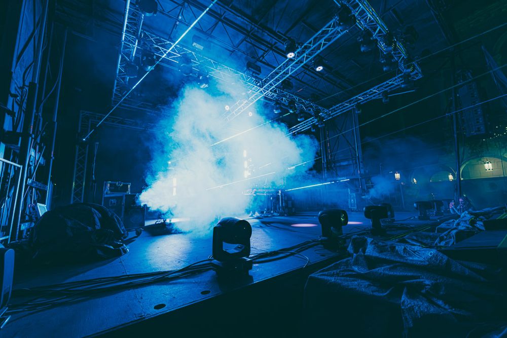 Empty stage illuminated by bright blue theatrical lighting and fog effects during a show setup.