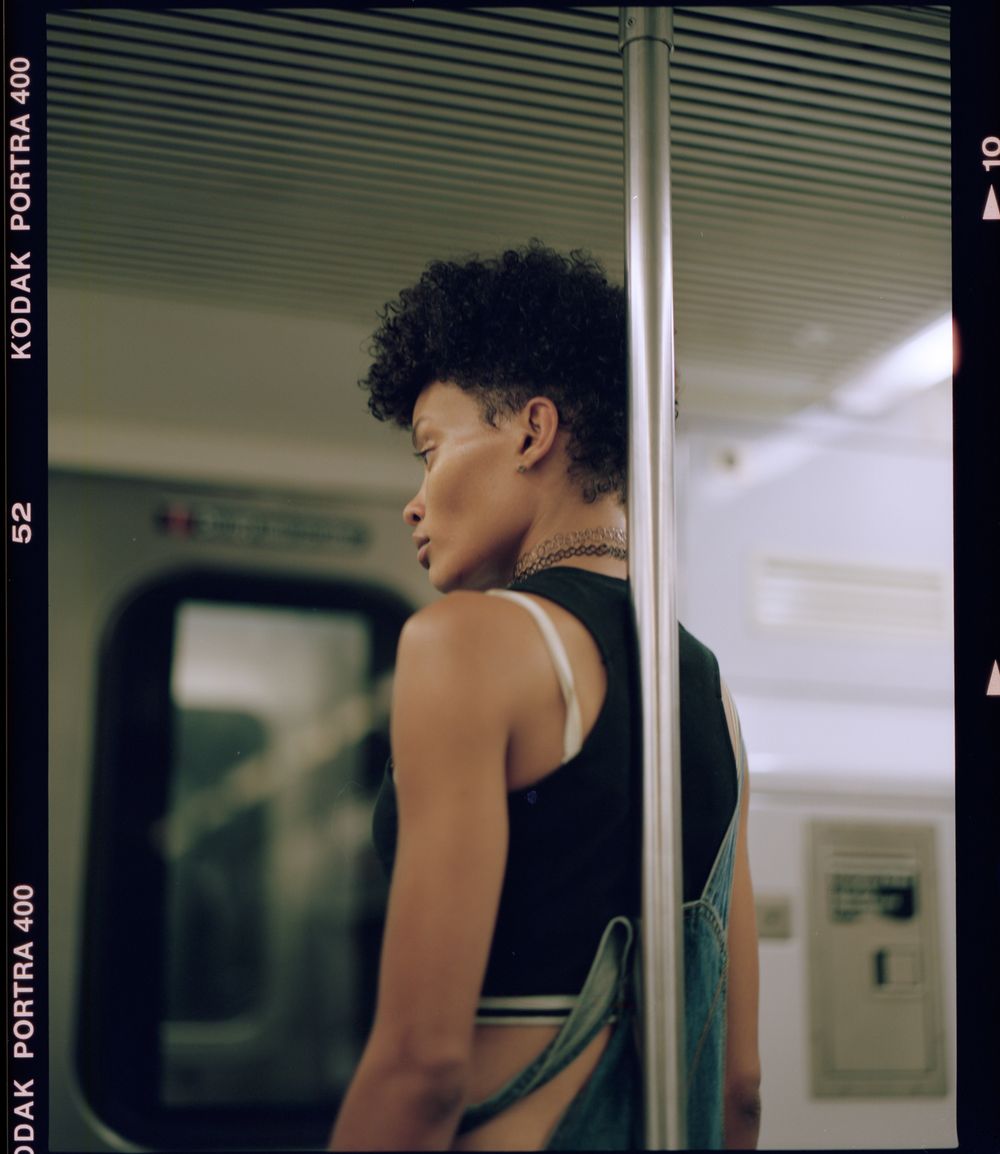 Side profile shot of person in tank top on subway train.