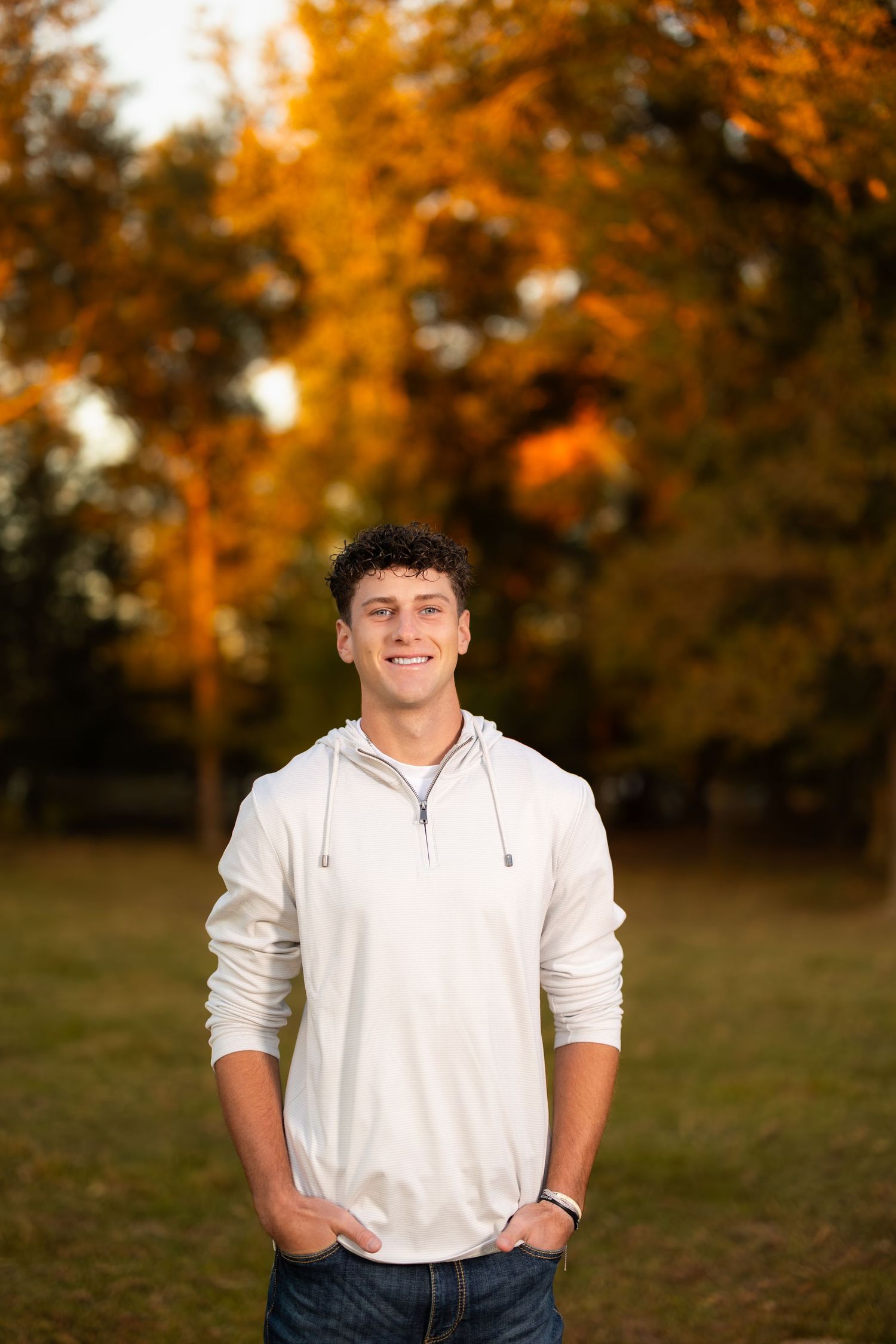 Autumn outdoor portrait with warm orange foliage in background.