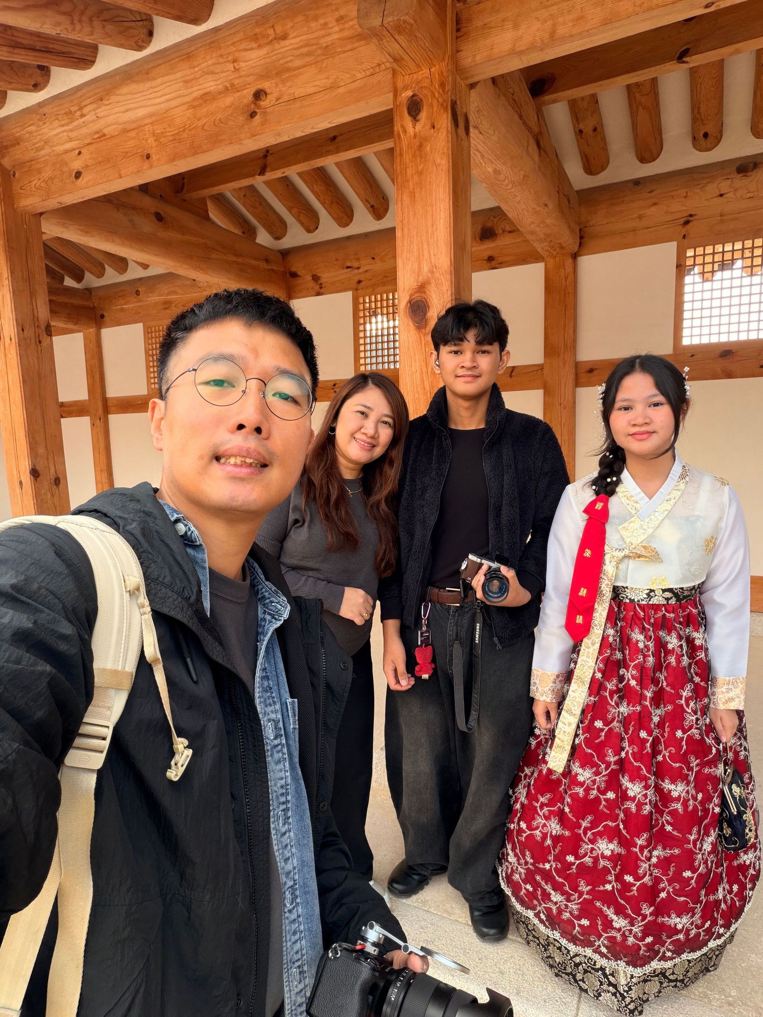 A group poses together in a traditional Korean hanok building with wooden beams and latticed windows.