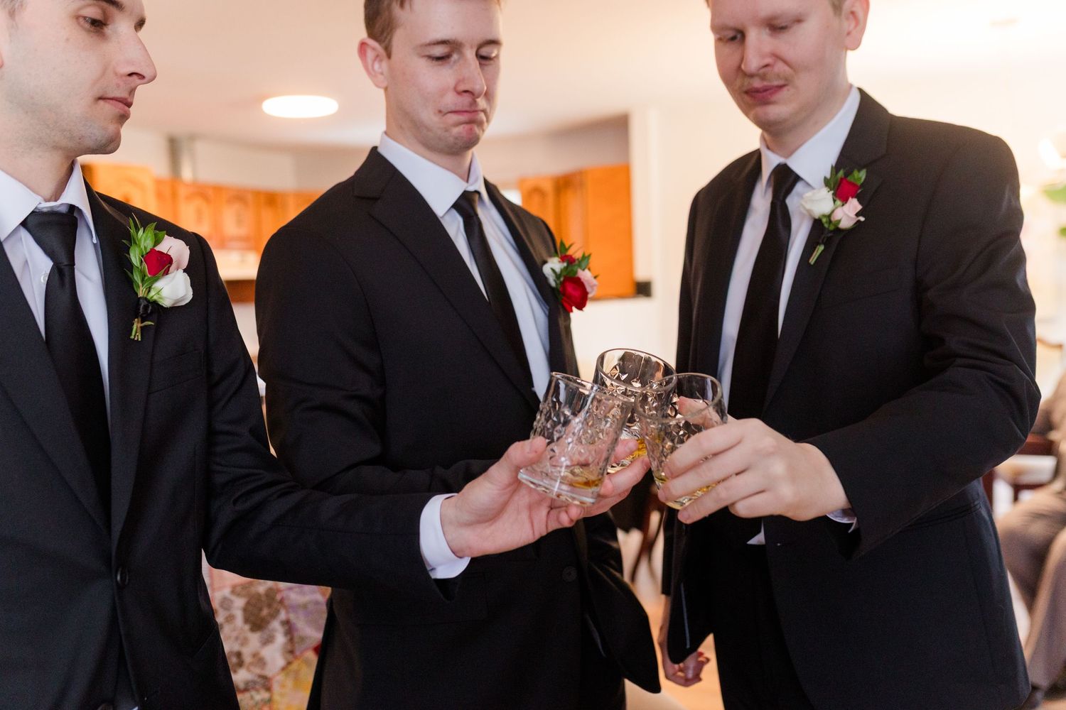 Groomsmen in black suits toasting with champagne glasses during a wedding celebration.