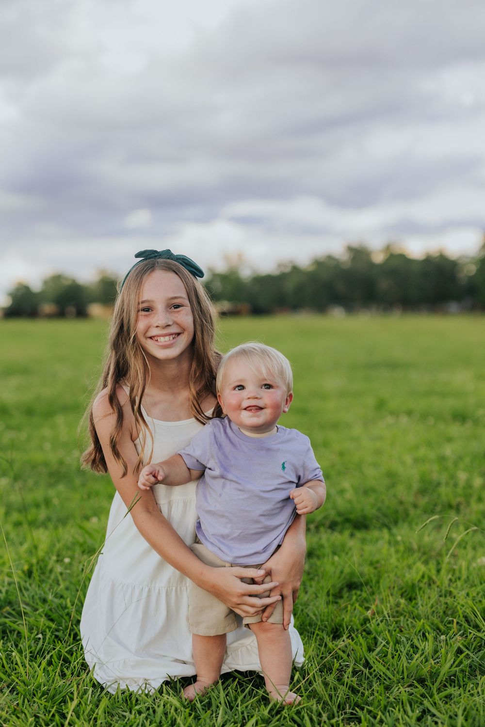 A tender moment captured in a grassy field on a cloudy day.