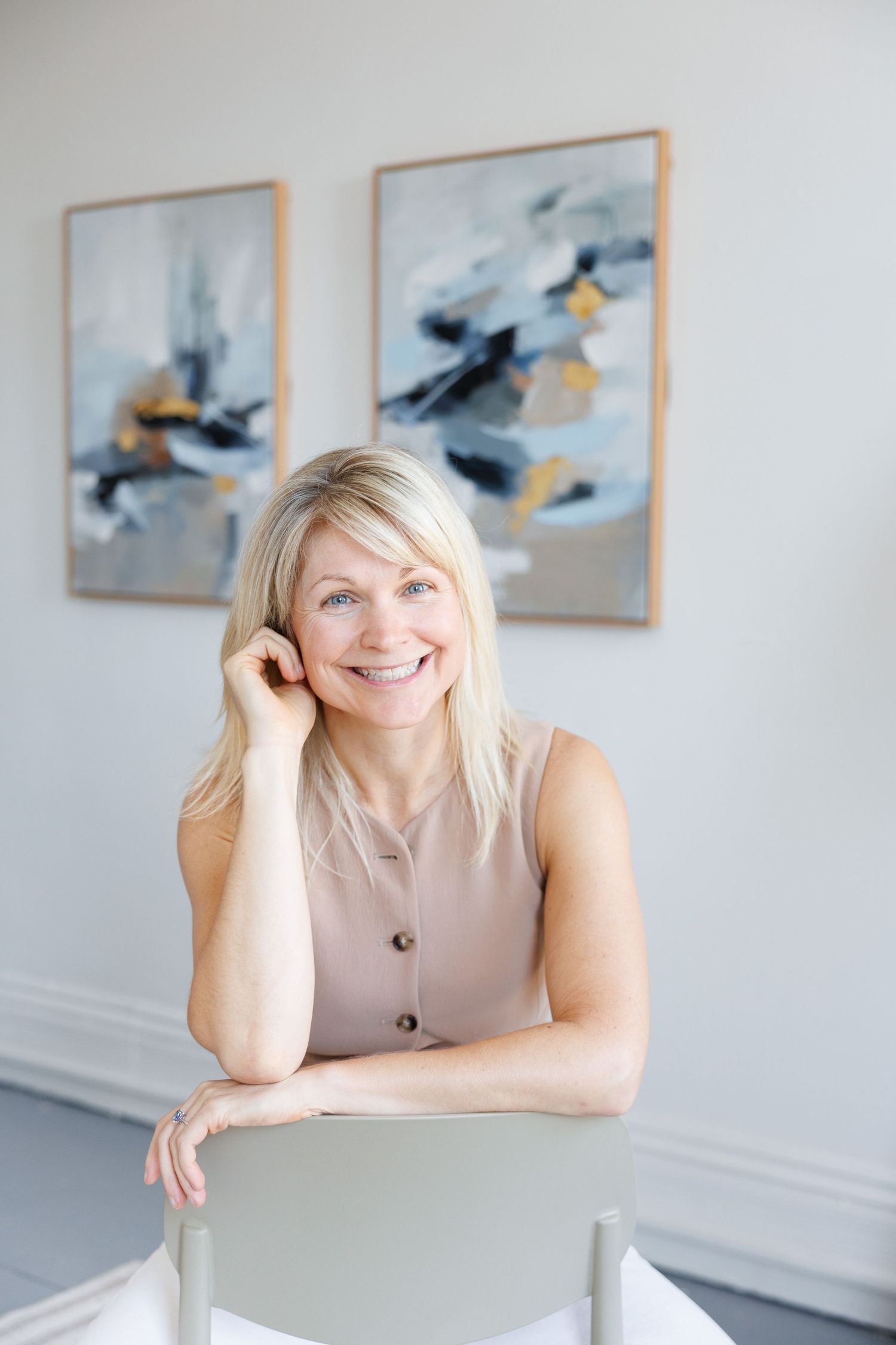 Professional headshots showing a person in a beige sleeveless top posing against a white wall with artwork displayed.