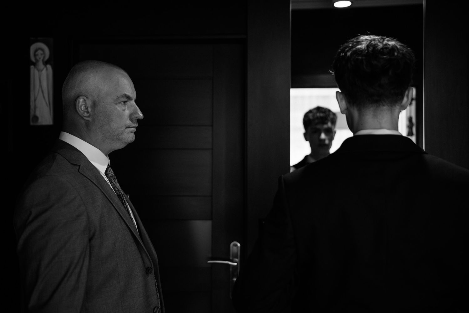A series of black and white film noir style photographs showing dramatic lighting and shadowy figures in a dark hallway.
