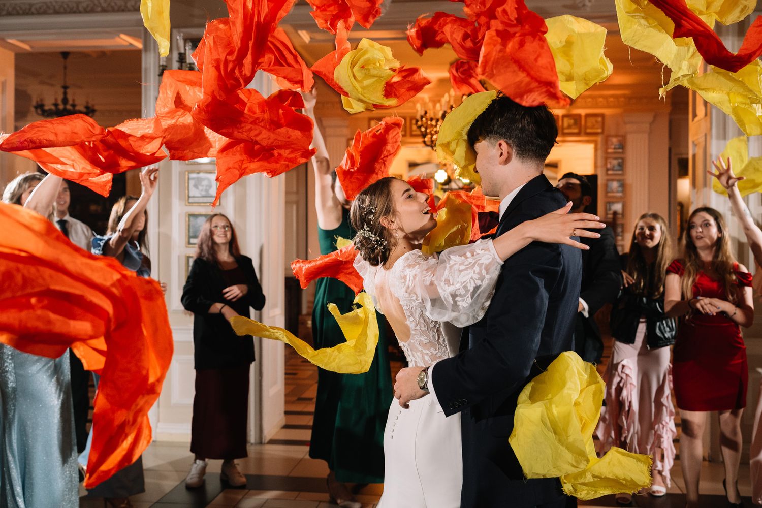 People dancing with flowing red and yellow silk fabric in an indoor performance space.