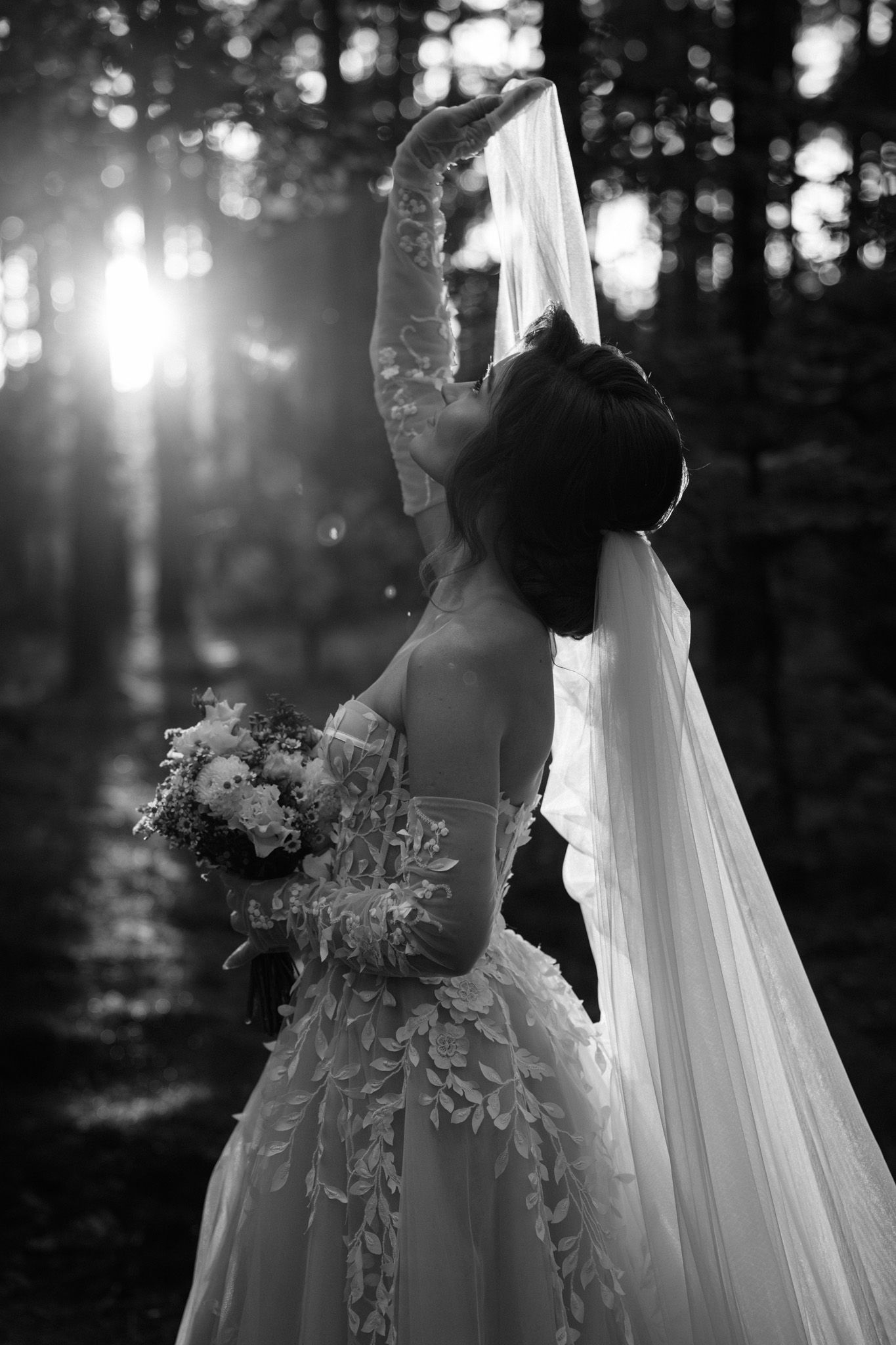 A dreamy black and white wedding photo sequence showing a flowing veil and elegant dress in sunlit woodland.