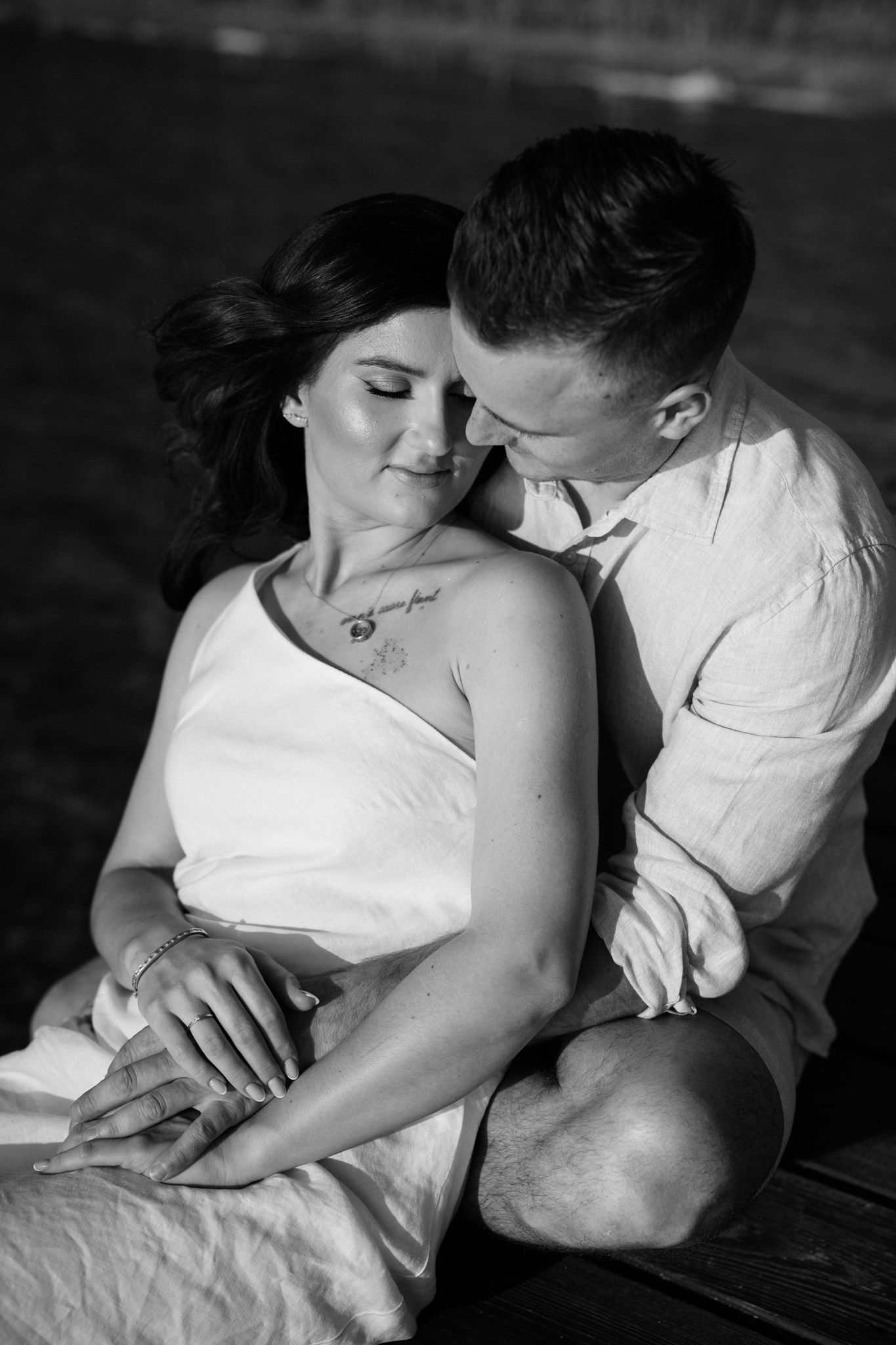 Black and white intimate couple photography series showing tender moments and gentle embraces on white bedding.