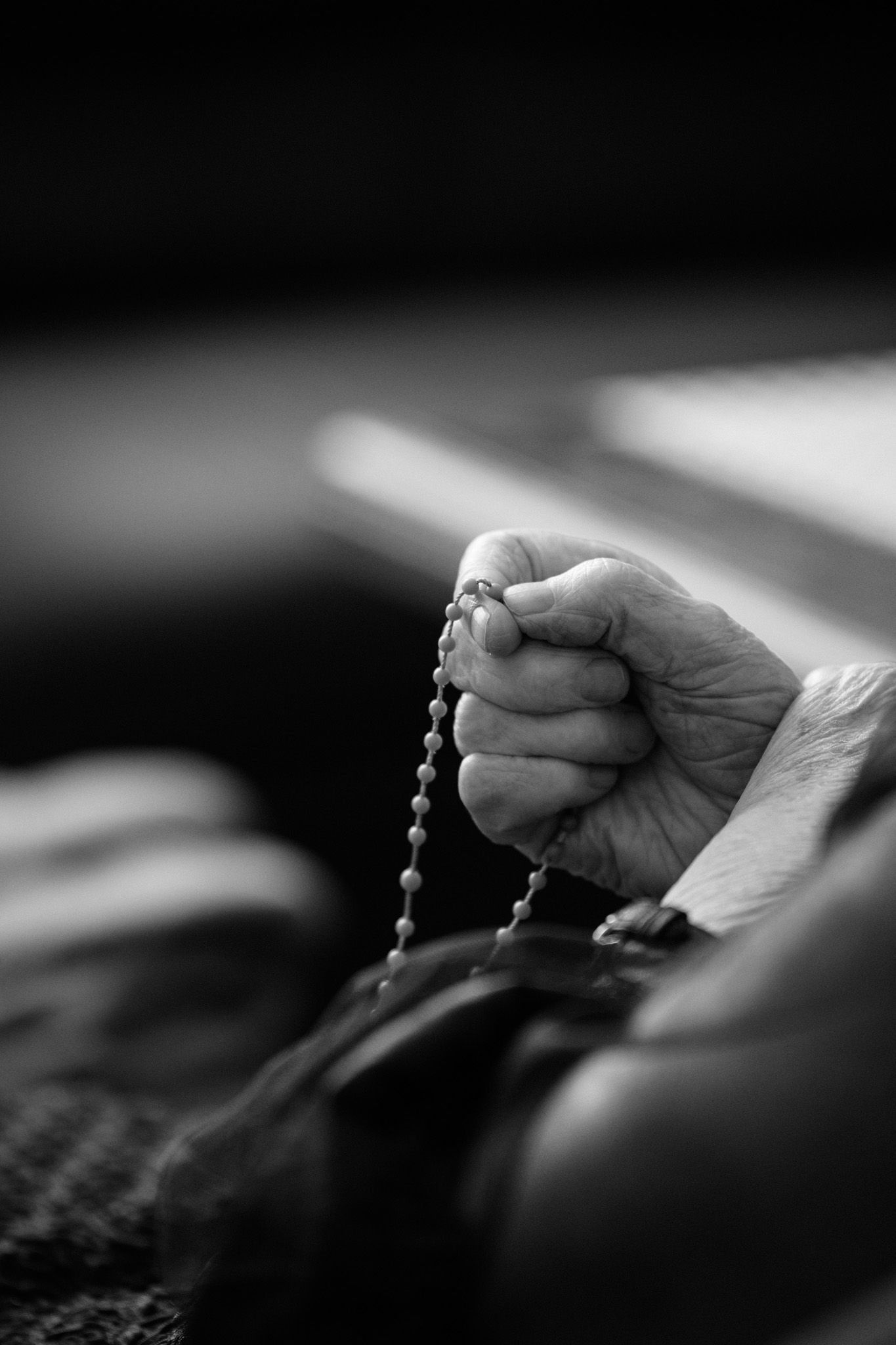 Black and white close-up of hands holding prayer beads in a spiritual moment of contemplation and devotion.