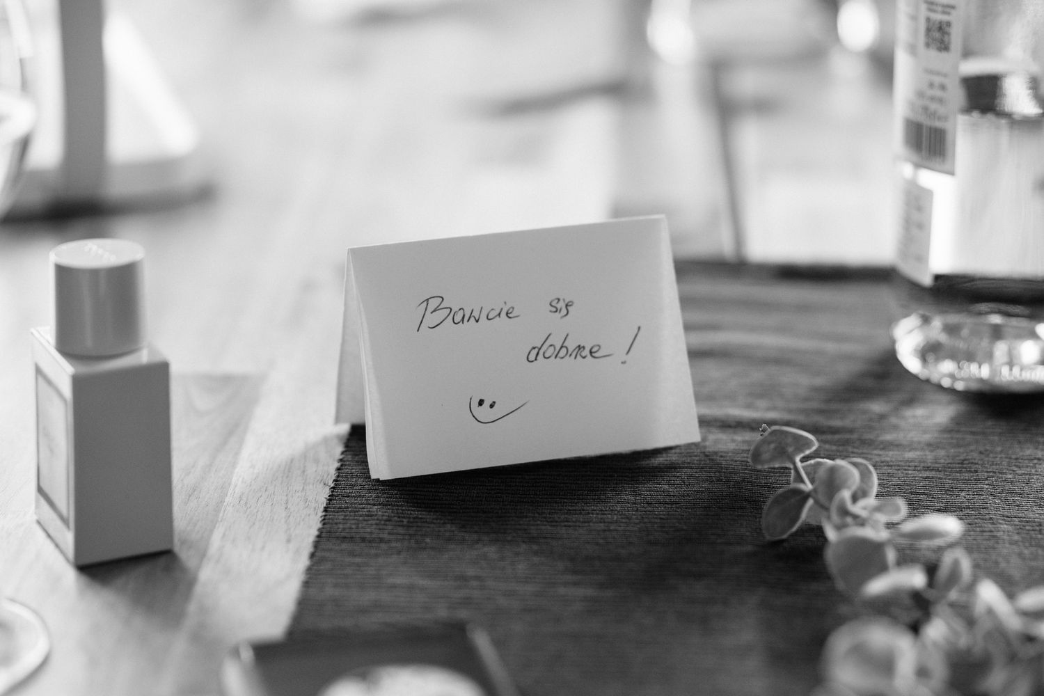 A close-up view of hands writing on paper with pens and office supplies scattered on a white desk surface.