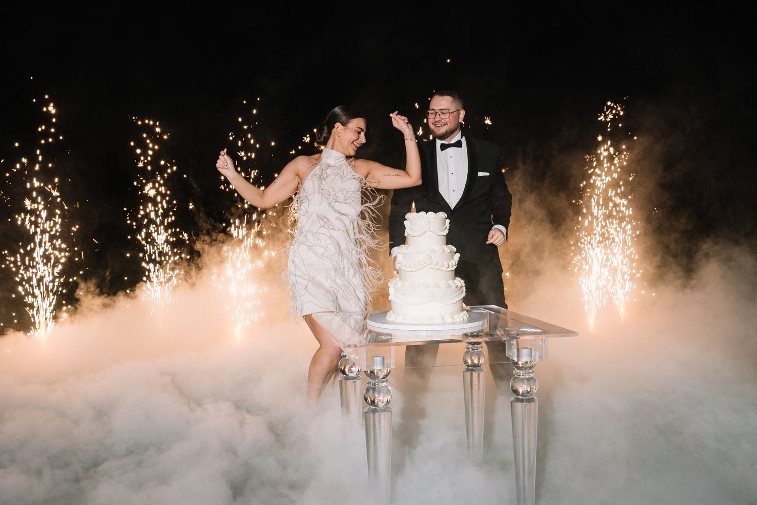 Couple dancing on a foggy dance floor with sparklers creating a magical wedding reception atmosphere.