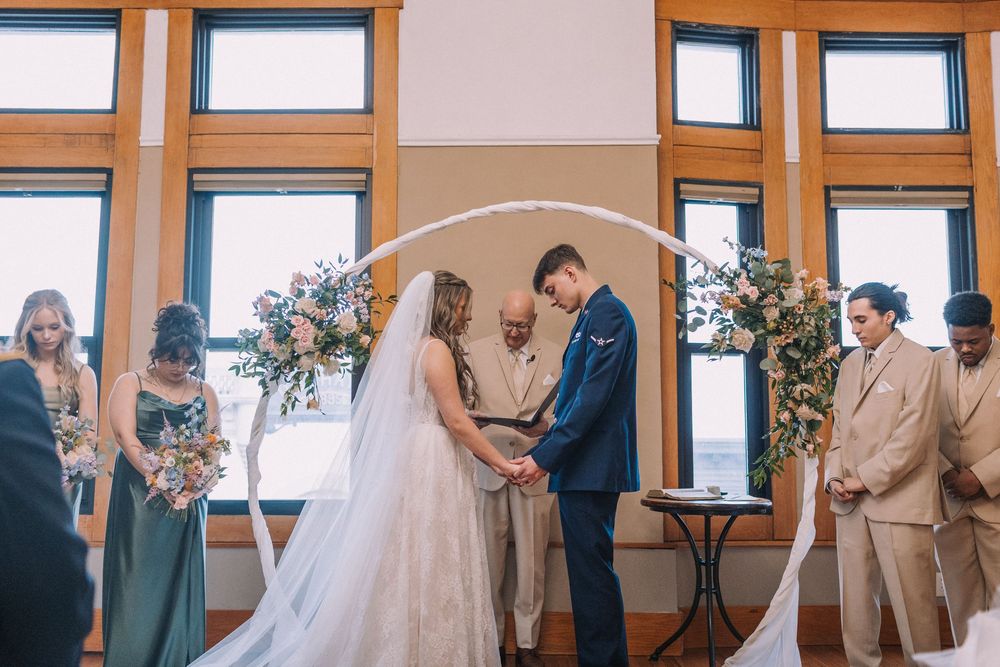 Wedding party lines up in a room with large windows and wooden trim.