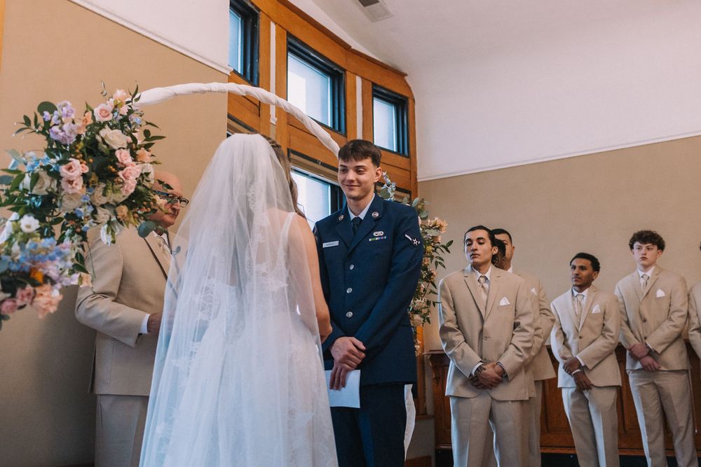 Wedding ceremony with bride in white dress and military groom in dress blues.