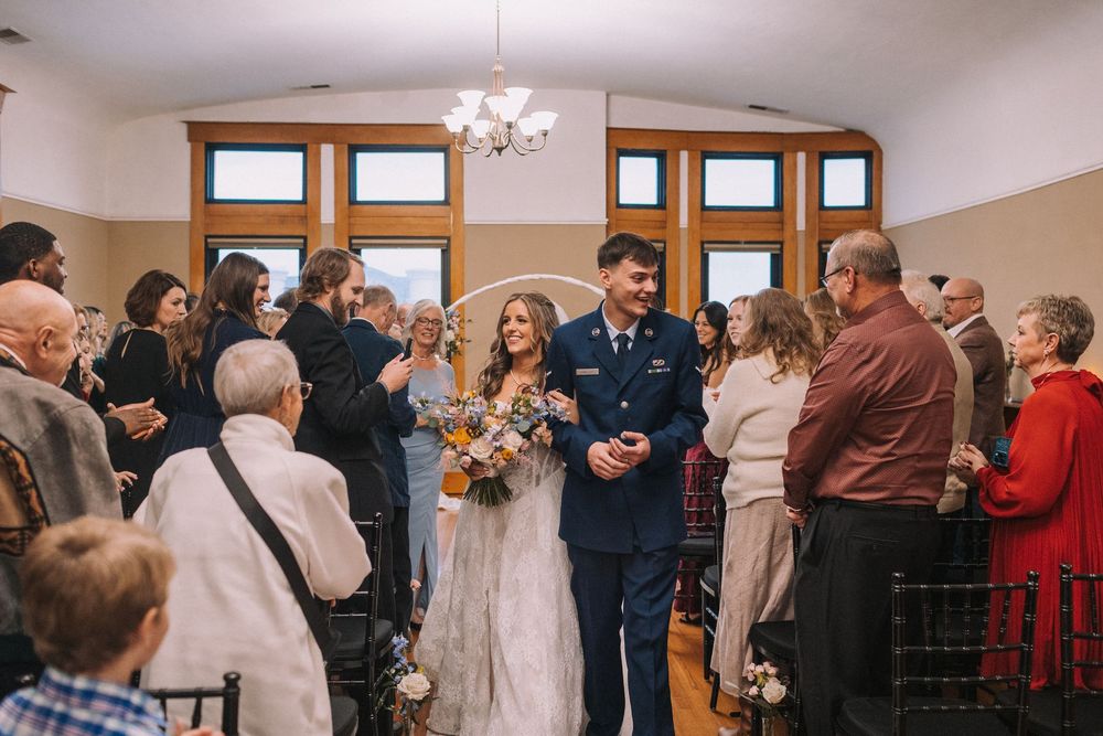 Wedding guests gather to witness ceremony in bright indoor venue.