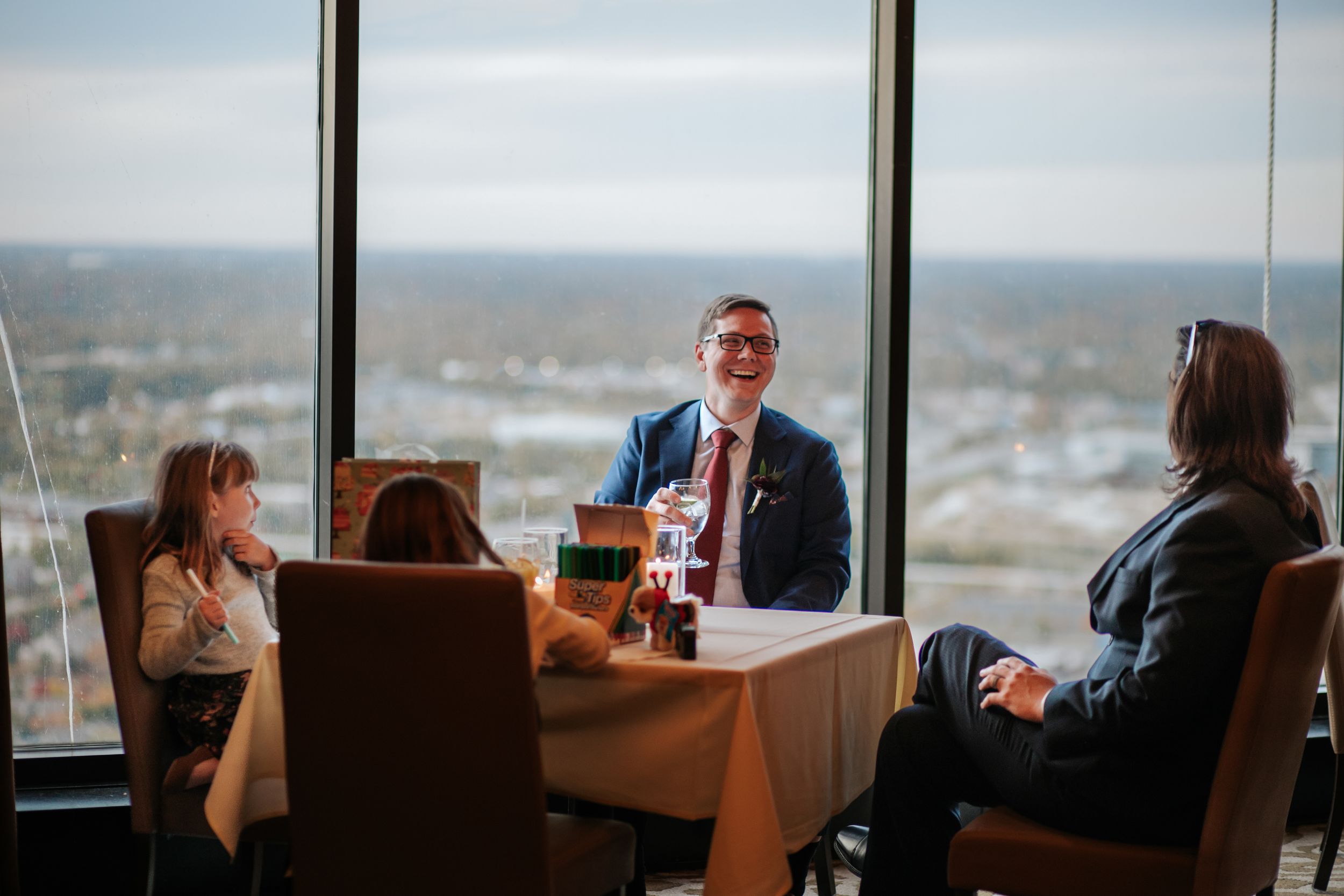 Business professionals seated at conference table in modern office with panoramic city views through large windows.