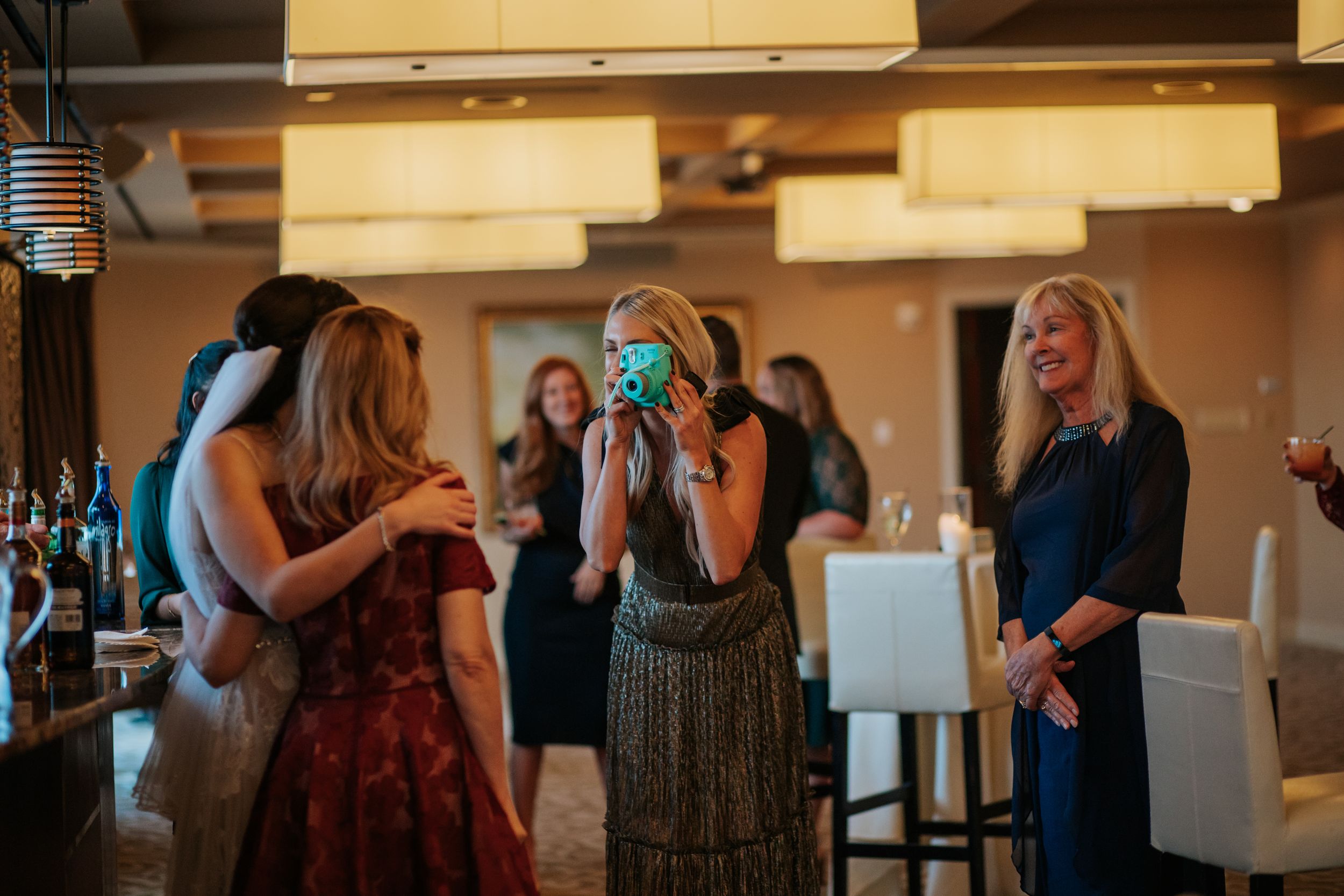 Wedding guests mingle and socialize during an elegant indoor reception with warm lighting and formal attire.