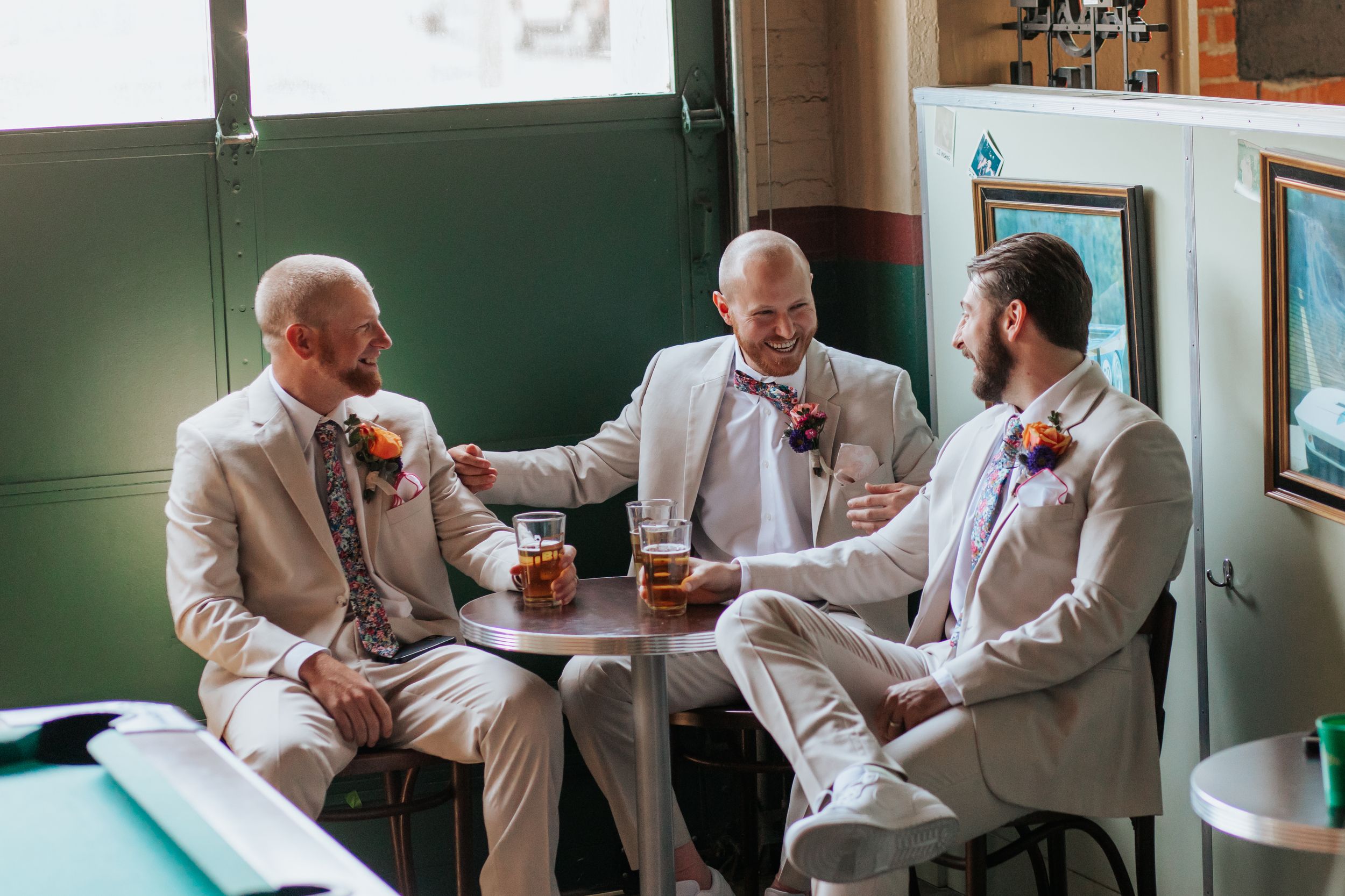 Three people in white shirts sit at a table having a discussion over drinks in a casual setting.