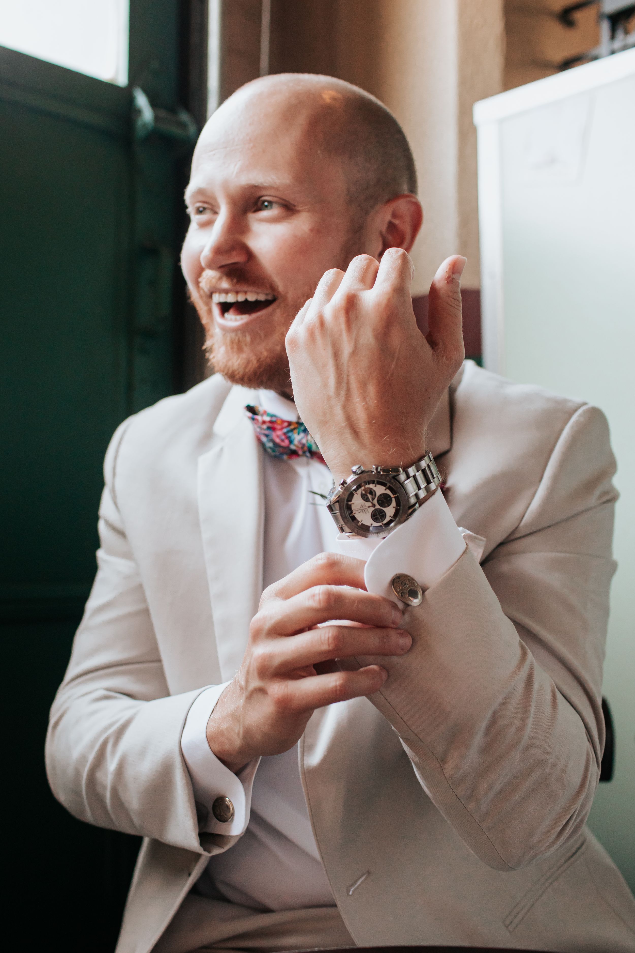 Close-up shots of someone in a white suit jacket checking their watch and smiling.