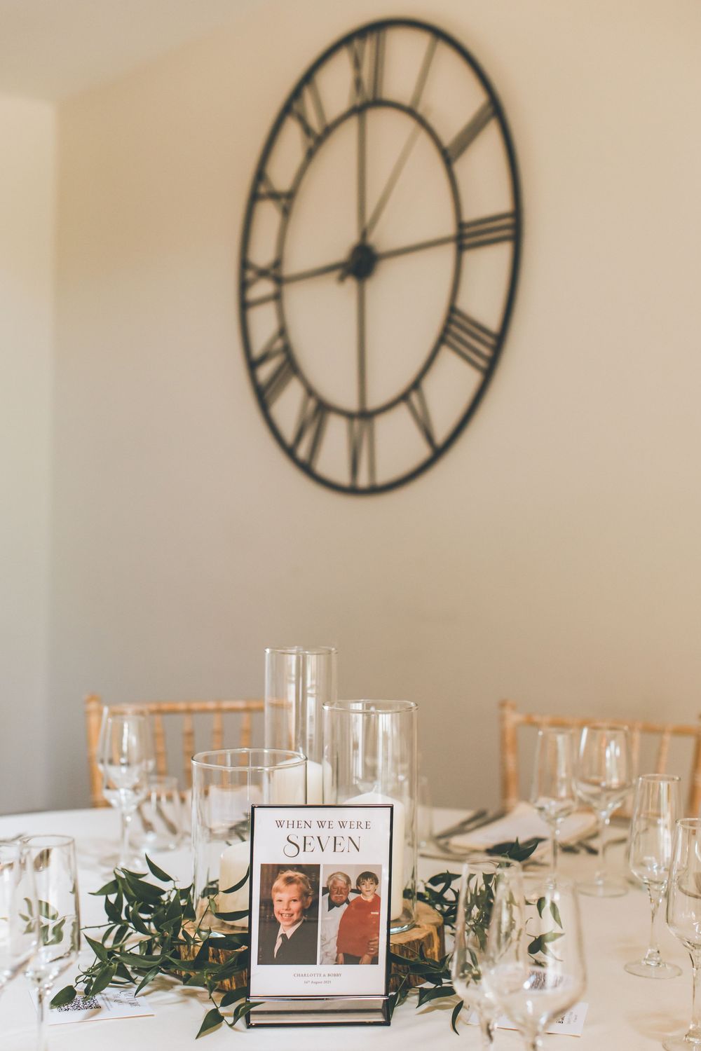 Elegant table setting with large wall clock and framed photos as centerpiece decor.