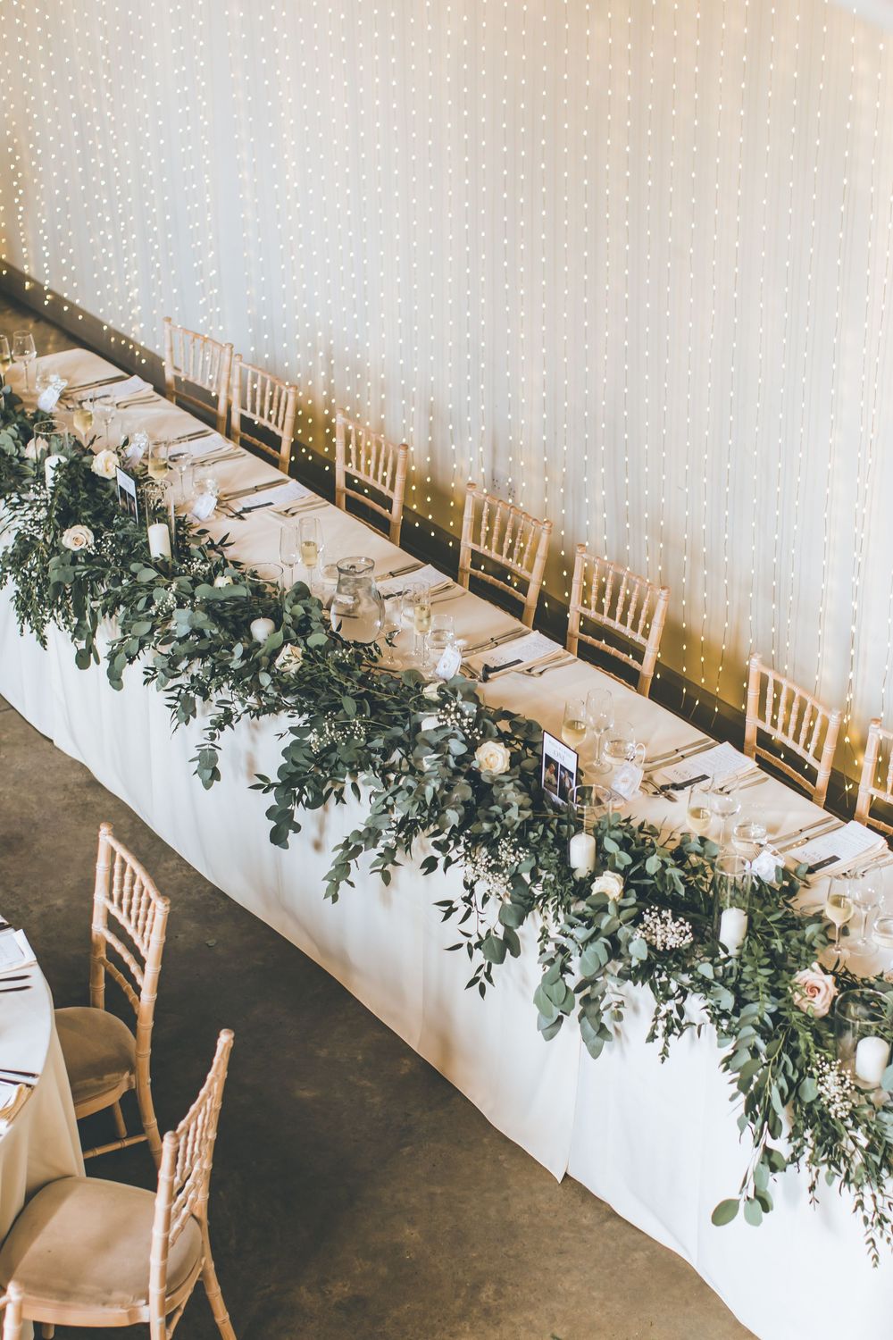 Wedding reception tables decorated with white linens and green floral arrangements.